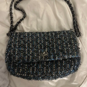 Blå och svart axelväska med kedja - Jättesnygg söndergaard väska! Bra skick men vissa trådar i tyget har gått upp men inget som stör funktionen och syns knappt! 