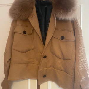 Beige jacka med pälsdetalj från Meotine - Säljer en snygg beige jacka från Meotine med en lyxig pälsdetalj på kragen. Jackan har en quiltad textur och knappar framtill. Kostar egentligen ca 3000 men säljer för 1000 + frakt. Pris kan diskuteras!Skriv vid frågor eller intresse💕 Inga defekter!