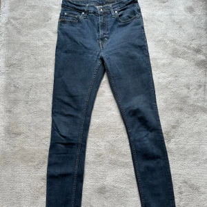 Mörkblå jeans från Tiger of Sweden - Snygga mörkblå jeans från Tiger of Sweden i modellen Kelly. De har en klassisk femficksdesign och en knappgylf. Perfekta för en stilren look.