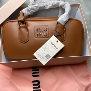 Brun handväska  - Säljer en stilren brun handväska. Väskan har en elegant design och en praktisk dragkedja inuti. Perfekt för att ge din outfit en lyxig touch.