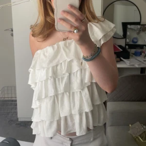 Vit volang one shoulder topp - En superfin vit topp med flera volanger, perfekt till vardag och fest! Den är använd en gång eftersom jag bara ville ha den på en fest, Skriv för frågor!
