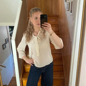 Beige knytblus i siden - En beige knytblus i siden med vida ärmar.