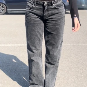 Svarta raka jeans - Säljer ett par svarta jeans med tvättad look och raka ben. Jeansen har klassisk femficksdesign, normal passform och hög midja. Perfekta till vardags för en avslappnad stil.