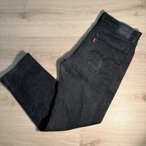 Svarta Levi's 511 jeans - Säljer ett par svarta Levi's 511 jeans med klassisk femficksdesign och rakt snitt. Jeansen har en diskret tvättad look och den ikoniska röda Levi's-lappen på bakfickan. Perfekta för en stilren vardagsoutfit. 32/30