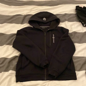 Svart hoodie från Sail Racing med dragkedja - Säljer en svart sailracibg hoodie med dragkedja. Tröjan har bra skick. Storlek 160. Hör av dig vid funderingar!