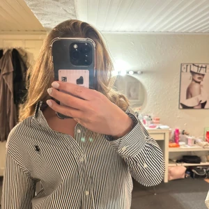 Randig skjorta från Polo Ralph Lauren - Säljer en klassisk svartvit randig skjorta från Polo Ralph Lauren med broderad logga på bröstet. Skjortan har lång ärm, knappar framtill. använd en gång inga slitage eller något! 