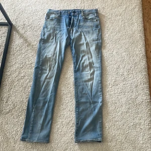 Ljusblå Levi's 501 jeans - Klassiska ljusblå Levi's 501 jeans med raka ben och femficksdesign. Jeansen har knappgylf och är tillverkade i slitstarkt denim. Perfekta för dig som gillar en tidlös och avslappnad stil.