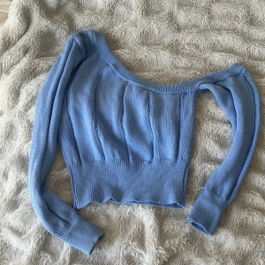 Ljusblå croppad stickad tröja (xs/s) - Superfin ljusblå croppad stickad tröja med bred, djup urringning. Tröjan har långa ärmar och ribbad nederkant, perfekt för en trendig look. Snygg att styla med både jeans och kjol.