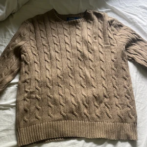 kabelstickad tröja från Polo Ralph Lauren - Säljer en klassisk beige kabelstickad tröja från Polo Ralph Lauren då den var för stor för mig bara prövat på den annars har så är den oanvänd. Pris kan diskuteras 