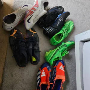 Bara dom gröna kvar - Säljer flera par fotbollsskor i olika färger och modeller. Här finns bland annat vita Nike med lila och röd detalj, svarta Nike, gröna Adidas och blå-röda Adidas Predator. Perfekta för dig som vill ha snygga och funktionella skor på planen.
