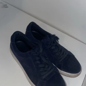 Vagabond mocka - Snygga mörkblå sneakers med snörning och rund tå. Skorna har en platt vit sula och är tillverkade i mocka. Perfekta för en stilren vardagslook.