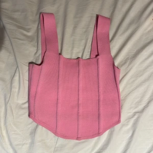 Rosa korsett-topp  - Säljer en rosa korsett-topp från Primark med breda axelband och markerade sömmar framtill. Toppen är croppad och har en strukturerad passform som ger en snygg siluett. Perfekt att styla med jeans eller kjol! Säljer den pga att den blivit för liten men sitter jätte fint på kroppen och är inte för tight eller lös. Den har används få gånger men ser helt ny ut. Köparen står för frakt💗 