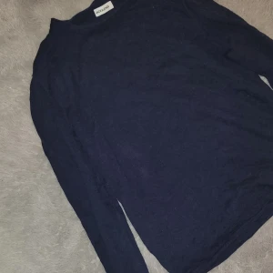 Mörkblå långärmad tröja från Jack & Jones - Säljer en enkel och stilren mörkblå långärmad tröja från Jack & Jones. Tröjan har rund halsringning och är tillverkad i ett mjukt material som passar perfekt till vardags. Klassisk passform och diskret design.