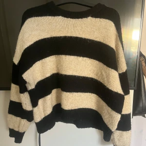 Randig stickad tröja från Culture - OBS!!! Sitter som en S skulle jag säga, vanligtvis har jag xs, men denna sitter bra och köpte den oversized. Säljer en mysig stickad tröja från Culture i svart och beige med breda ränder. Tröjan har en avslappnad passform och långa ärmar, perfekt för kyliga dagar. 
