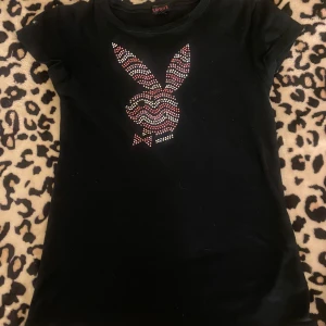 Svart Playboy Tshirt  - Svart Tshirt från Playboy med rhinestones. Bra skick förutom att några rhinestones ramlat av(bild2) står att det är storlek S men skulle säga att den sitter mer som M!💗