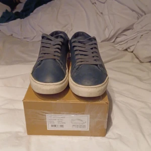 Marinblå sneakers från Kronstadt - Säljer ett par stilrena marinblå sneakers från Kronstadt, modell Connor. Skorna har vit platt sula, rund tå och snörning. Perfekta för en avslappnad och snygg look. Färg: navy/white. I storlek 43 köptes för ca 1000 kr andvända i speciela tillfällen är prutbar vid snabbaffär skriv om du har några frågor eller funderingar 