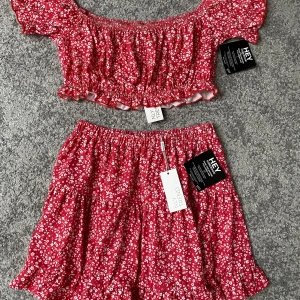 Rött sett - Blommigt set, aldrig använt! Prislapp kvar                              Storlek M i toppen och S i kjolen! 