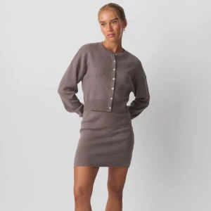 Brun stickad kofta och kjol-set från NA-KD - Säljer ett brunt stickat set från NA-KD med croppad kofta och matchande kjol. Koftan har långa ärmar, rund halsringning och knappar framtill. 💗 Aldrig använt! Köpt för 800kr