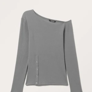 Grå ribbad oneshoulder-tröja med knappar - Säljer en grå ribbad oneshoulder-tröja från Monki med lång ärm och dekorativa knappar längs sidan.☀️ Tröjan har en tight passform och är perfekt för dig som vill ha en stilren men unik look. As cool och unik med en slit med knappar🔥 Vid frågor skriv, pris går att diskuteras😇💓 Aldrig använd🙏