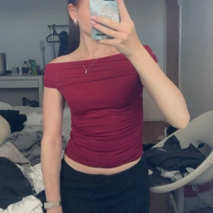Vinröd offshoulder topp från SHEIN - Säljer en vinröd offshoulder topp från SHEIN i storlek XS. Toppen är tight och croppad med snygg drapering längs sidorna. Perfekt för dig som gillar en stilren och trendig look. Materialet är mjukt och stretchigt, vilket gör den superbekväm att bära.