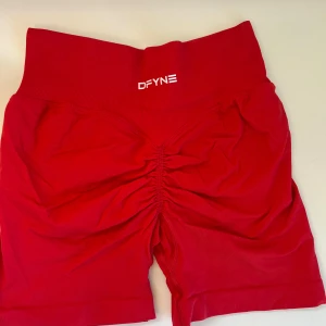 Röda shorts från DFYNE - Riktigt snygga röda seamless shorts från DFYNE med låg midja och scrunch-detalj bak. Stretchigt material som sitter tight och framhäver formerna. Perfekta för gymmet eller andra träningspass. Logga framtill i vitt.