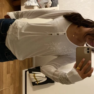 Vit långärmad topp med spets  - Säljer en vit långärmad topp från Desigual med fina spetsdetaljer på ärmarna och broderade blommor framtill, tröjan har knappar och är i bra skick 💕 skriv för bilder eller mer info