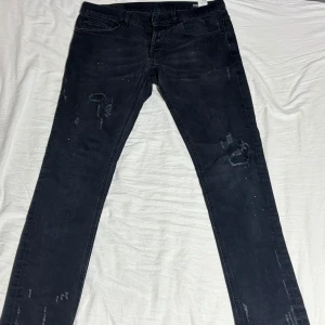 Dondup jeans - Svarta skinny jeans från Dondup med slitna detaljer och diskreta färgstänk. Jeansen har klassisk femficksdesign, smal passform och är tillverkade i stretchigt material för en bekväm känsla.  9/10 skick vilket är sällsynt för sånnahär jeans!!