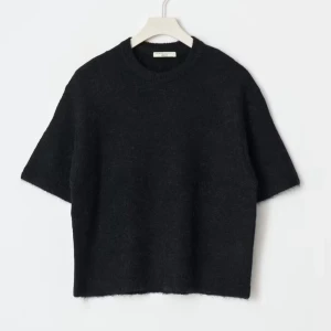 Svart stickad kortärmad tröja - Svart stickad tröja från Gina Tricot med korta ärmar och rund hals. Tröjan har en loose passform och är tillverkad i ett mjukt, fluffigt material som ger en chill och trendig vibe. Perfekt att styla med mönstrade byxor eller jeans.