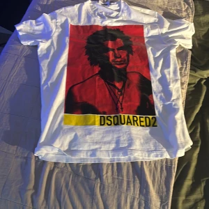Vit DSQUARED2 t-shirt med tryck XL - Vit t-shirt från DSQUARED2 i storlek XL med stort grafiskt tryck framtill i rött, svart och gult.  Tröjan använd 1 gång så väldigt bra skick på tröjan nypris 2200