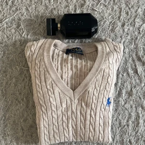 Brand New Polo Ralph Lauren Cable Knit Sweater – Never Worn! - Elevate your wardrobe with this authentic Polo Ralph Lauren cable knit sweater in a timeless cream/beige color. This piece is brand new and never worn, in perfect condition with no flaws, tags still attached (if applicable).  ✔️ Size: (Add size here) ✔️ Material: Soft, breathable 100% cotton ✔️ Color: Elegant neutral beige with iconic blue Polo logo ✔️ Style: Classic V-neck, cable knit design – perfect for layering or wearing on its own ✔️ Fit: Regular, flattering fit – both casual and smart ✔️ Condit