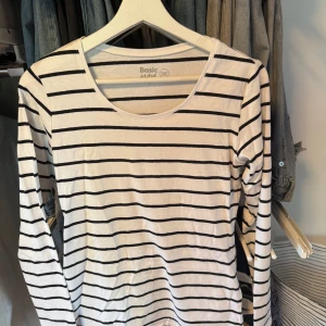 Randig långärmad tröja från basic you (Ullared) - Vit långärmad tröja från Ullared Basic You med svarta horisontella ränder. Perfekt för en clean och avslappnad look. Rund halsringning och klassisk passform som funkar till allt. Tyvärr är det en liten fläck som syns på bild 2 