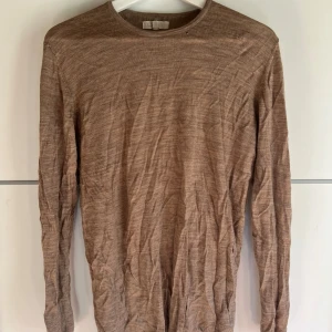 Beige långärmad tröja från S.C.W - En tunn, beige långärmad tröja från S.C.W i storlek L. Tröjan har en enkel och stilren design med rund halsringning och är tillverkad i ett mjukt, stickat material. Perfekt för lager-på-lager och chill vardagsstil.