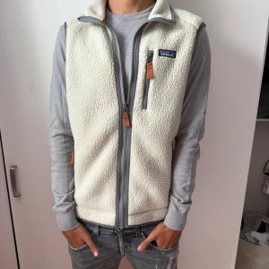 Patagonia fleeceväst - Säljer en ljusbeige fleeceväst från Patagonia i storlek M passar dig som har S också. Västen har grå detaljer, hög krage och tre fickor med dragkedja och snygga läderdetaljer på zipparna. Nyskick använd max 5 gånger, nypris-1400 mitt pris 900 kan diskuteras vid snabba affärer 