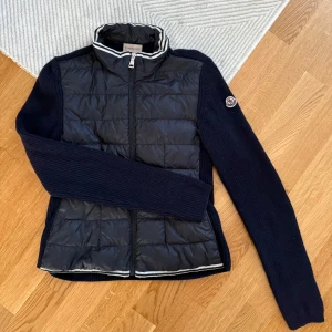 Monclercardigan - Snygg mörkblå cardigan från Moncler med stickade ärmar och rygg😍Den är i storlek 164 men passar mig som har XS/S. Inga synliga defekter, det enda skulle vara att den lilla Moncler lappen högst upp innanför kragen sitter lite löst🩷Skriv för fler bilder🩷