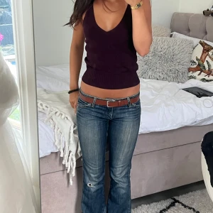 Vinröd stickad linnetopp - Snygg vinröd stickad linnetopp med smala axelband och djup v-ringning. Modellen är croppad och har bred ribbad kant nedtill för en tightare passform. Perfekt till jeans eller kjol för en trendig look. Storlek s men passar mig som är xs