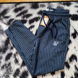 Siksilk byxor  - Ett par skit snygga mörk blå byxor med vita ränder från siksilk. Storlek M passar 172-180. Om ni har några frågor så är det bara att fråga