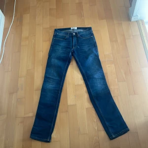 Blå jeans från Acne Studios - Snygga blå jeans från Acne Studios med klassisk femficksdesign och raka ben. Jeansen har en mörk tvätt med lätt slitning och kontrastsömmar. Perfekta för dig som gillar stilrena och tidlösa jeans med en modern touch.
