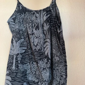 Mönstrat linne Desmond & Dempsey x H&M - Skön och luftig linnetopp med tunna axelband. Toppen är mörkblå med ljusblått tropiskt mönster med palmer och blad. Perfekt för varma dagar, tillverkad i mjuk bomull. Skitsnygg att styla med jeansshorts eller kjol.