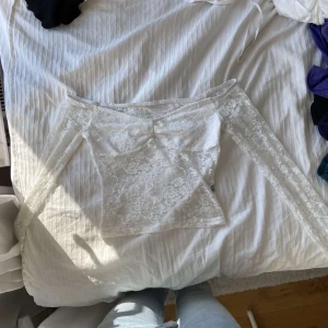 Vit spetsig offshoulder topp - Säljer en superfin vit offshoulder topp i spets med blommigt mönster. Toppen har långa ärmar och är figurnära med transparent känsla. Perfekt för dig som vill ha en romantisk och trendig look med extra detaljer.