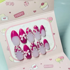 Rosa press-on naglar med pärlor & rosetter - Söta press-on naglar i mandelform med rosa och ljuslila bas, dekorerade med små vita blommor, pärlor och ljusrosa 3D-rosetter. Perfekt för dig som vill ha en gullig och unik nageldesign utan att gå till salong.