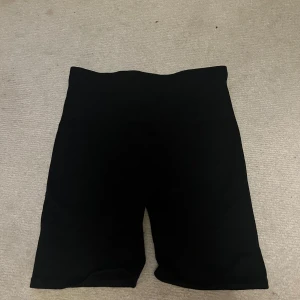 Svarta cykelshorts med hög midja från stadium - Svarta cykelshorts med hög midja och tight passform. Perfekta för träning eller chill dagar. Mjukt och stretchigt material som sitter skönt mot kroppen. Klassisk look utan synliga detaljer eller mönster. Kan dras upp blir då korta shorts. Aldrig kommit till användning