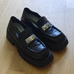 Whimsical skor - Svarta chunky loafers från Chiara Ferragni i skinn med grov sula och silverfärgade detaljer framtill. Köpte för 1000 men tyvär inte min size, står 37 men är mindre. Är riktig läder