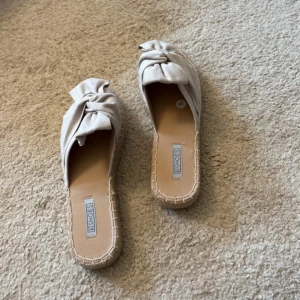 Beige sandaler - Snygga beige sandaler från Nelly med bred knutdetalj i tyg över foten. Helt nya, aldrig använda 