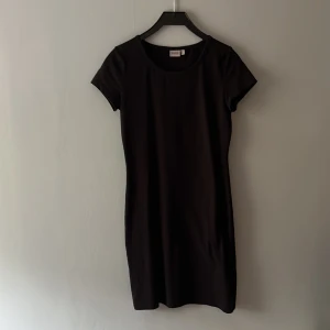 Svart kortärmad klänning från RYVLS💕 - Enkel och stilren svart kortklänning från RYVLS med rund halsringning och korta ärmar. Klänningen har en rak passform och är tillverkad i ett mjukt material som känns skönt mot.💕
