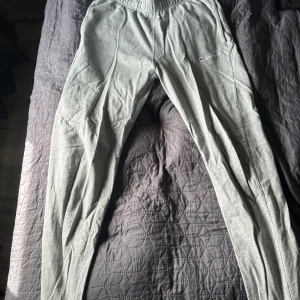 Grå mjukisbyxor från Champion M - Grå mjukisbyxor från Champion i 100% bomull. Byxorna har resår i midjan och broderad Champion-logga på ena benet. Perfekta för chill eller träning, med en klassisk och enkel look.