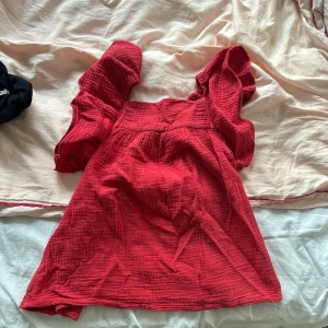 Röd blus med puffärmar - Supersöt röd blus med puffiga kortärmar och fyrkantig ringning. Tillverkad i mjuk, strukturerad bomull som ger en avslappnad och trendig vibe. Perfekt att styla med jeans eller kjol för en cool look. passar mig med xs