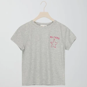 Grå t-shirt med rosa tryck Gina Tricot - Gråmelerad t-shirt från Gina Tricot med korta ärmar och rund hals. På bröstet och ryggen finns rosa tryck med texten 'MA CHÉRIE' och en stjärna. Skön och enkel modell i mjuk bomull, perfekt till jeans eller shorts. Säljs för att den är för liten för mig!