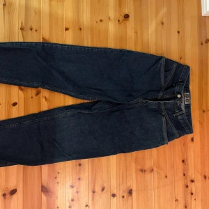Mörkblå Jeans Forenza  - Fina mörkblå jeans från Forenza i vidare modell. Långa ben som blir snygga att vika upp. Storlek osäker men suttit bra på W27-32. 