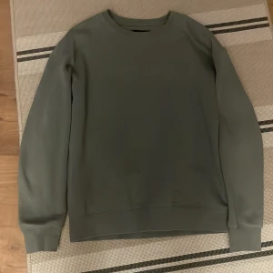 Grå sweatshirt från Jack & Jones - En stilren grå sweatshirt från Jack & Jones i storlek S. Tröjan har rund halsringning, långa ärmar och ribbade muddar vid ärmslut och nederkant. Perfekt för en avslappnad look och enkel att matcha med jeans eller joggers.