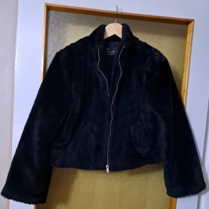 Svart pälsjacka från Even&Odd - Mysig svart pälsjacka från Even&Odd med dragkedja framtill och hög krage. Jackan är croppad och har en fluffig känsla som ger en cool look. Väldigt fint skick- och väldigt bekvämt:)